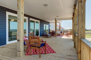 A covered deck with wooden furniture and a red patterned rug. - Blue Oasis - 2500 Bienville Blvd (Dauphin Island)