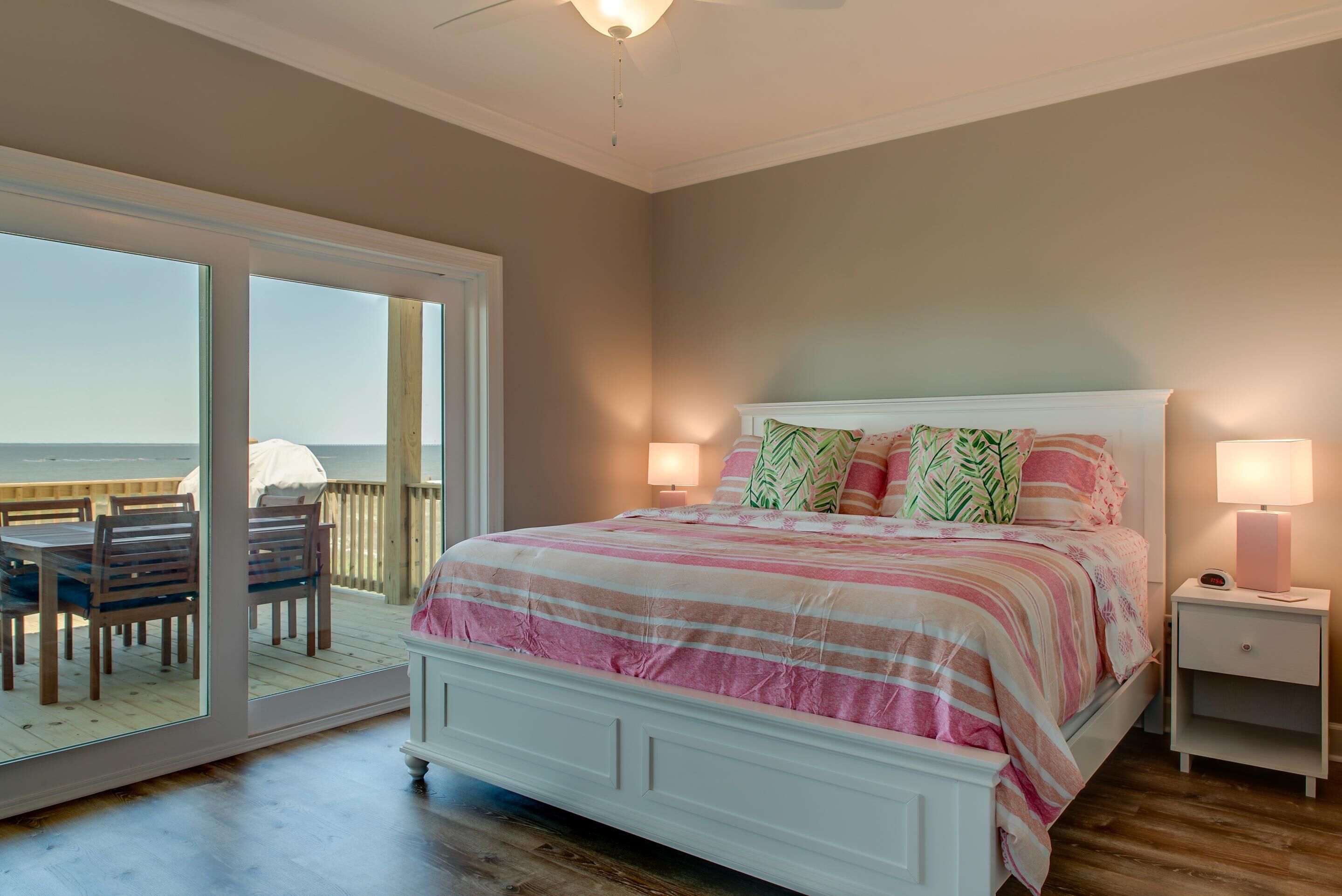 A bedroom with a large sliding glass door leading to a balcony with a view of the ocean.