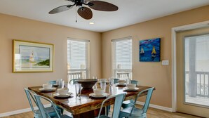 A dining room with a wooden table set for four, light blue chairs, and a ceiling fan.