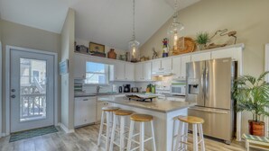 A modern kitchen with white cabinets, a stainless steel refrigerator, and a central island with bar stools.