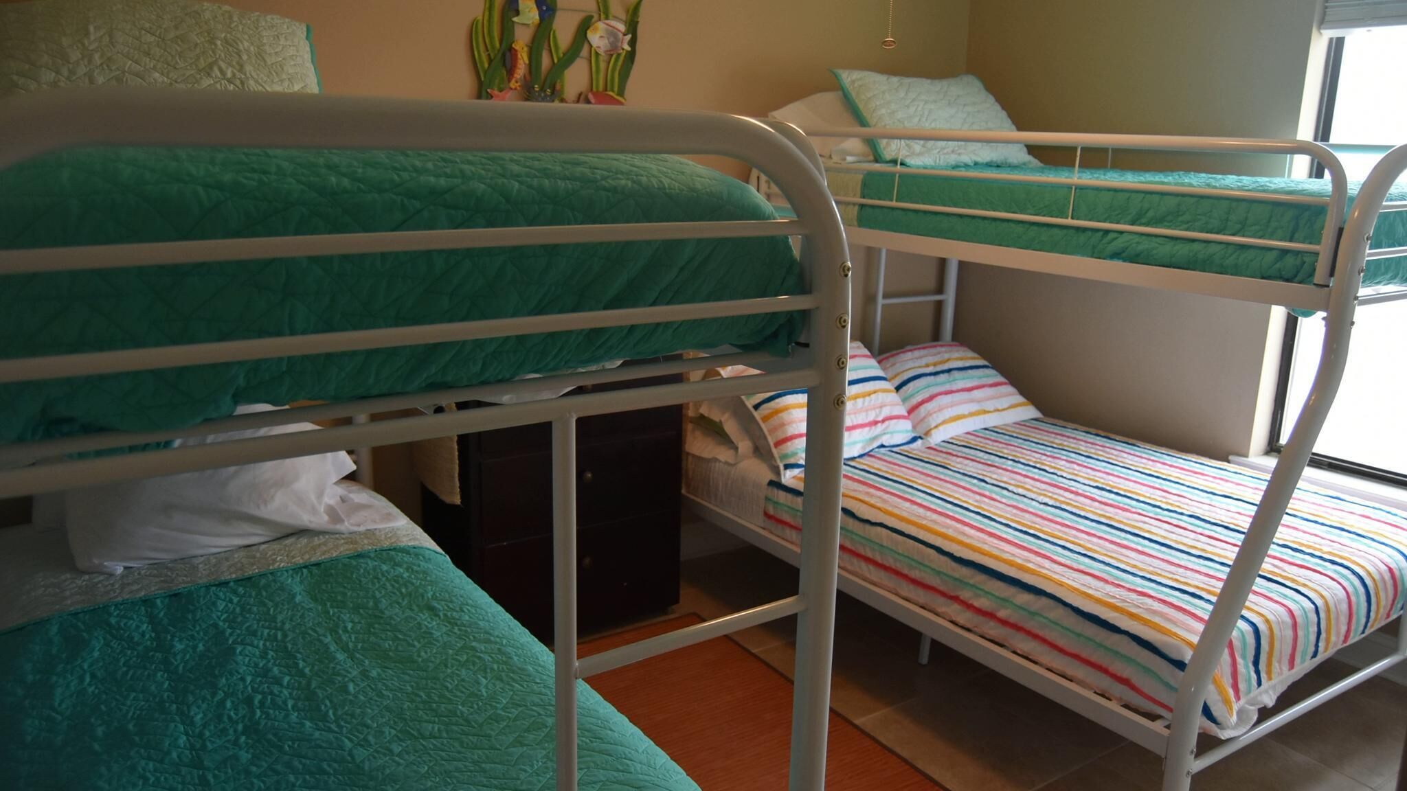 A bunk bed room with green bedding and a striped bedspread.