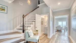 A staircase with wooden steps and white railings, leading to a dining area with a table and chairs. - Endless Possibilities-1809 Bie (Dauphin Island)