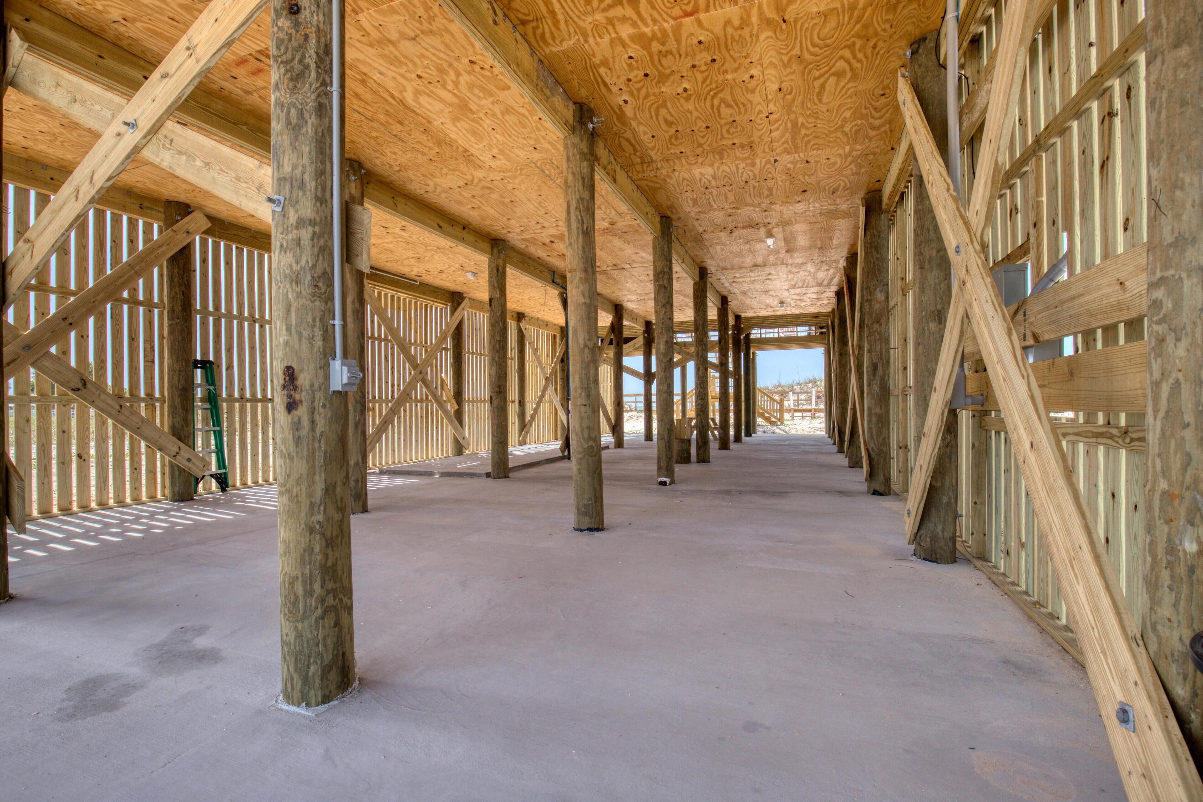 Un intérieur spacieux avec un plafond haut soutenu par des poutres en bois, un plancher en béton et de grandes fenêtres qui laissent entrer la lumière naturelle.