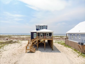 A beachfront house with a wooden deck and a staircase leading to a second floor. - Endless Possibilities-1809 Bie (Dauphin Island)