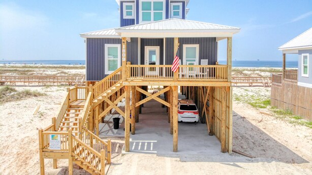 A beach house with a wooden deck, a flag, and a view of the ocean. - Endless Possibilities-1809 Bie (Dauphin Island)