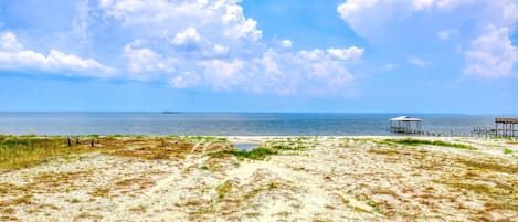 A beach with a sandy path leading to a wooden structure.