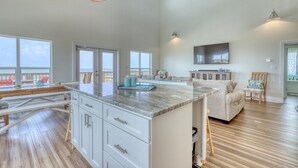 A spacious kitchen with a large island, white cabinetry, and a dining area with a sofa and chairs.