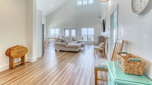 A spacious living area with a high ceiling, a large sofa, a dining table, and a wicker basket.