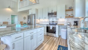 A spacious kitchen with white cabinets, a stainless steel refrigerator, a microwave, and a double oven.