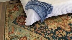 A bedroom with a bed, a nightstand, a lamp, and a patterned rug.