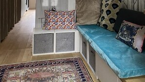 A modern living room with a built-in bench, a patterned rug, and a staircase with wooden beams.