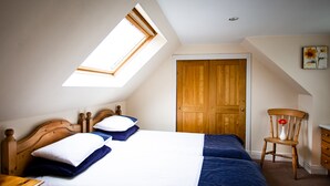 A bedroom with a skylight, a wooden door, a chair, and a dresser. - Comfy 3-bedroom Cottage in Newtonmore, Cairngorms (Newtonmore)