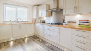 A modern kitchen with white cabinets, a stainless steel range hood, and a wooden countertop. - 3 bedroom accommodation in St Bees, near Whitehaven (St Bees, near Whitehaven)