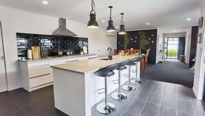 Eine moderne Küche mit einer zentralen Kochinsel, Barhocker und Pendelleuchten.