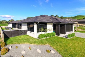 A modern two-story house with a covered patio, a driveway, and a well-maintained lawn.