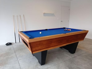 A pool table with a blue felt surface, surrounded by a light-colored floor. - House of Hope - Spa Pool, Sleeps 12 (Rotorua)