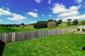 A grassy field with a wooden fence and trees in the background.