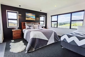 Relax in this serene bedroom with a large bed, nightstands, and a beautiful view of the surrounding landscape.