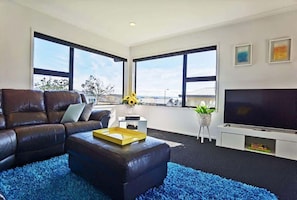 Relax in this stylish living room with a large sofa, flat-screen TV, and beautiful views of the outdoors.