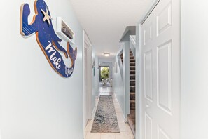 Un couloir décoré avec des motifs d’étoiles de mer et de sirènes, un tapis et un escalier.