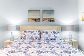 Une chambre à coucher avec un lit, deux tables de chevet et deux lampes fixées au mur.