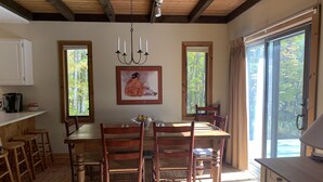 A dining area with a wooden table and chairs, a chandelier, and a painting on the wall.