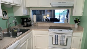 A compact kitchen with white cabinets, a built-in dishwasher, a stove, and a sink. - Oceanfront Paradise Awaits You! Walk directly to the beach from property (New Smyrna Beach)