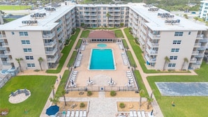 A multi-story hotel with a central swimming pool, outdoor seating areas, and a landscaped courtyard. - Oceanfront Paradise Awaits You! Walk directly to the beach from property (New Smyrna Beach)