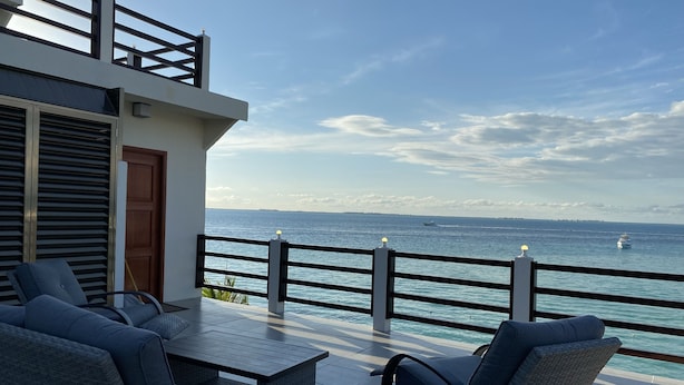 Un balcon doté de mobilier d’extérieur, d’une balustrade et offrant une vue sur la mer.
