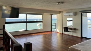 Une pièce spacieuse dotée d’une grande fenêtre donnant sur la mer et les bateaux.