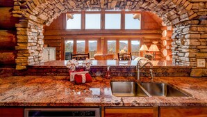Una cocina con arco de piedra, encimeras de granito, pileta de acero inoxidable y vista a las montañas.