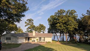 Une maison de plain-pied avec un porche à l’avant, un garage et une pelouse.