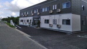 Un bâtiment moderne doté d’un toit plat, de plusieurs unités de climatisation et d’une entrée sécurisée par un portail.