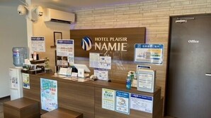 Un comptoir d’accueil d’hôtel avec une pancarte indiquant « HÔTEL PLAISIR NAMIE ».