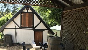 A covered outdoor seating area with a wooden table and wicker chairs, a wooden door, and a lattice structure.