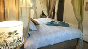 A bedroom with a bed, a chandelier, and curtains.