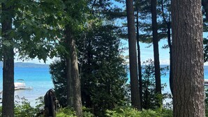 A forested path leading to a body of water with a dock visible in the distance. - Historic Glen Lake Cottage with Private Waterfront Access (Glen Arbor)