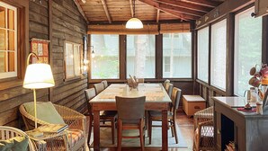A wooden cabin interior with a dining table, chairs, and a fireplace. - Historic Glen Lake Cottage with Private Waterfront Access (Glen Arbor)