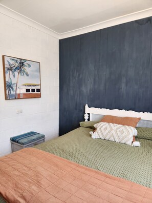 Ein Schlafzimmer mit einem Bett, einer Bank und einem Wandbild.