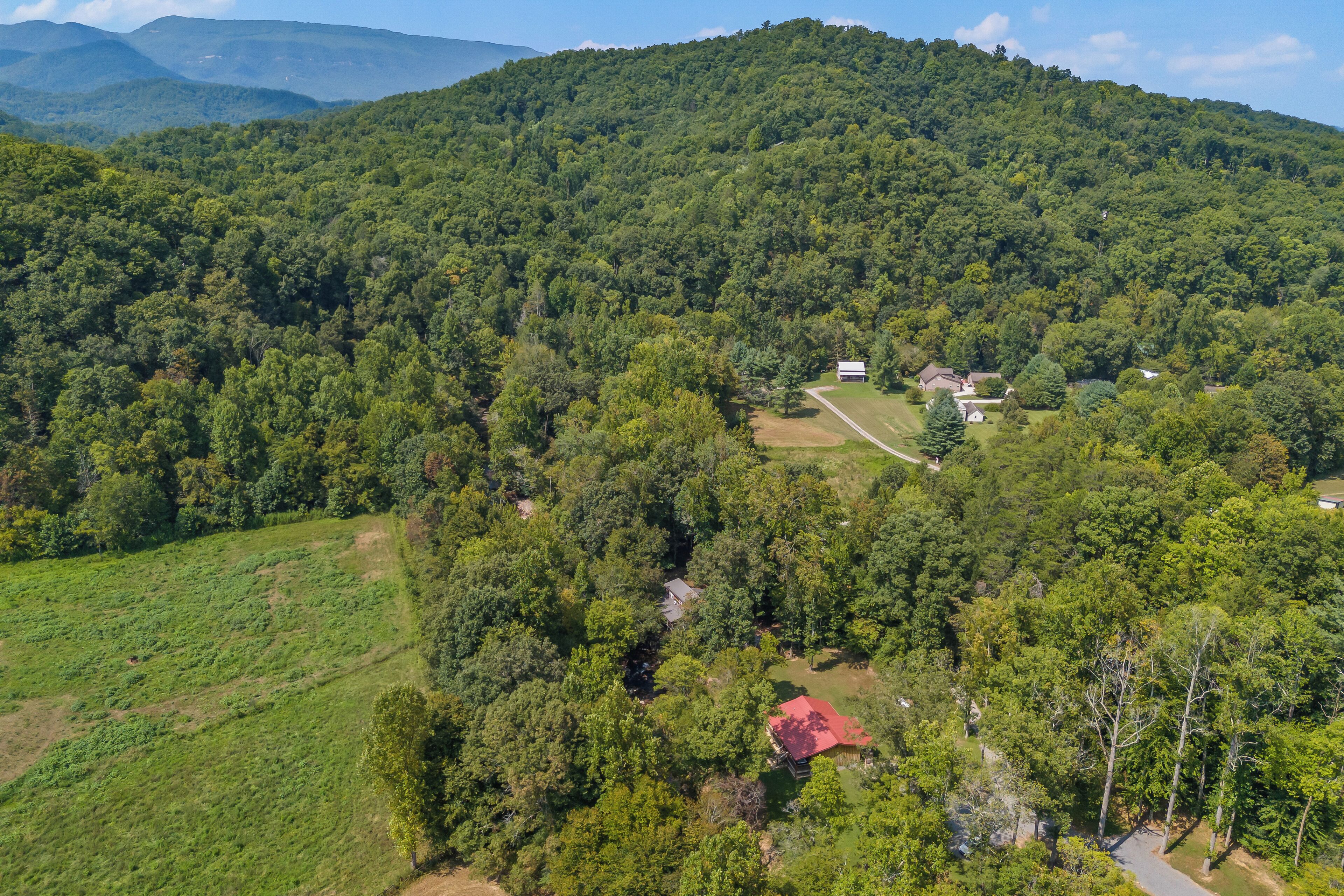 An aerial view of a rural area with a small cluster of buildings surrounded by dense forest.