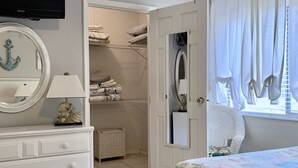 Ein Schlafzimmer mit Bett, Schminktisch, Fernseher, Kleiderschrank und einem Fenster mit Vorhängen.