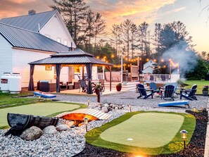 A cozy backyard with a covered patio, outdoor seating, and a putting green.