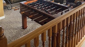 A spacious living room with a foosball table, two sofas, and a large window offering a view of the outdoors. - 7 Bedroom Spacious Lead Home with Game Room and Hot Tub (Lead)
