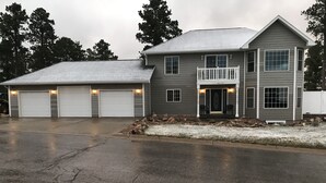 A two-story house with a garage, a front porch, and a driveway. - 7 Bedroom Spacious Lead Home with Game Room and Hot Tub (Lead)