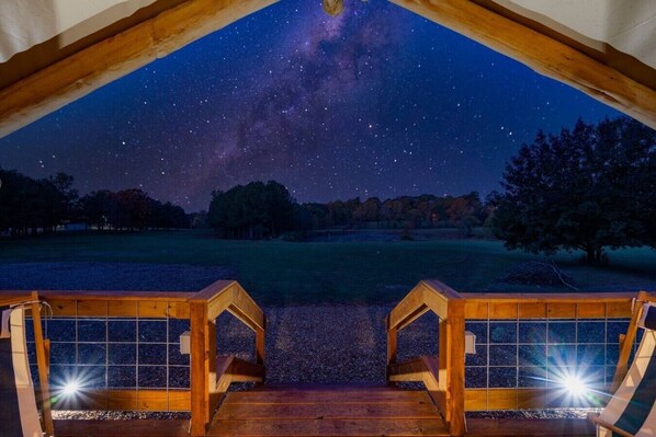Una terraza de madera con vista al cielo nocturno, estrellas y la Vía Láctea.