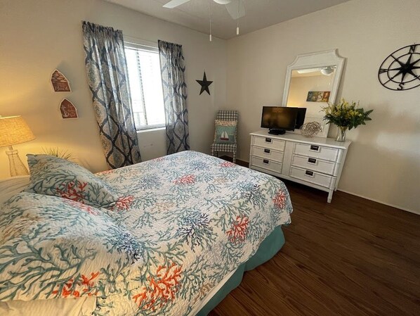 A bedroom with a bed, a dresser, a television, a star decoration, and a window with curtains. - Horizon East 704 - Oceanfront in Garden City Beach, SC (Garden City)