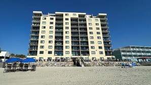 A multi-story hotel with balconies, a beach in the foreground, and a clear blue sky. - Horizon East 704 - Oceanfront in Garden City Beach, SC (Garden City)
