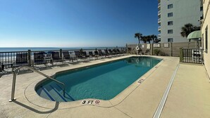 A pool area with a view of the ocean, a fenced deck, and a building with multiple floors. - Horizon East 704 - Oceanfront in Garden City Beach, SC (Garden City)