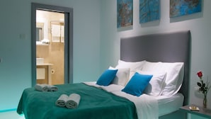 Ein modernes Schlafzimmer mit einem Bett, Kissen, einem Nachttisch und einer Vase mit einer Rose.