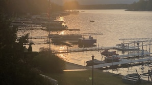 Ein Yachthafen mit vertäuten Booten, einem klaren Himmel und einer untergehenden Sonne über dem Wasser.